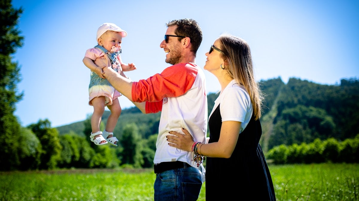 man in white and red polo shirt carrying girl in blue denim jeans during daytime
